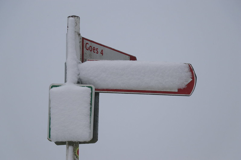 Drie verkeersbordjes, 2 besneeuwd, op de 3e is 'Goes 4' goed leesbaar